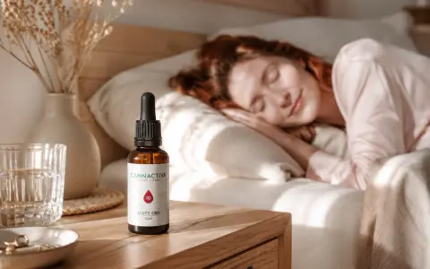 Una mujer duerme plácidamente. A su lado, en la mesita de noche, un frasco de aceite CBD, ideal para saber como tomar aceite de cbd para dormir y disfrutar de un descanso reparador.