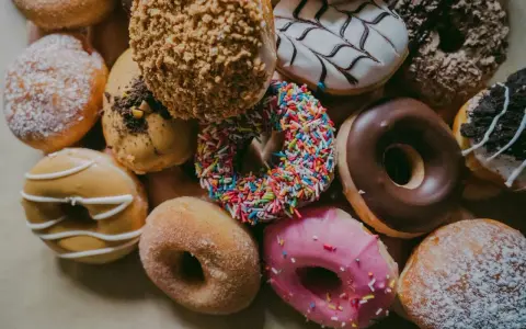 Kolorowe pączki z posypką, lukrem i cukrem pudrem. Zastanawiasz się, ile kalorii ma pączek?