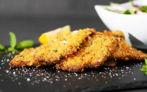 Cotoletta alla palermitana dorata e croccante, guarnita con limone e menta.