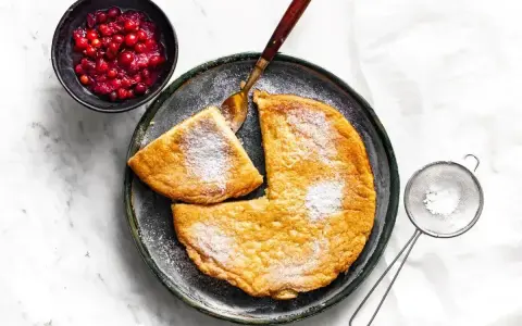 Puszysty omlet z airfryer, posypany cukrem pudrem, podany z żurawiną. Idealny na śniadanie.