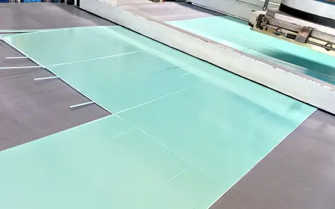 Große, hellgrüne Platten aus PVC-Schaum werden in einer Produktionsanlage zugeschnitten.