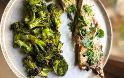 Brocoli al horno, tierno y dorado, junto a un filete de pescado con hierbas frescas.