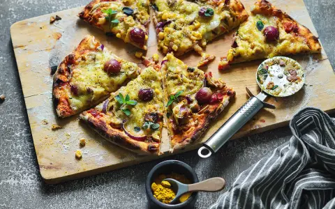 Domowa pizza z kurczakiem, kukurydzą i czerwoną cebulą, pokrojona na kawałki, gotowa do podania.