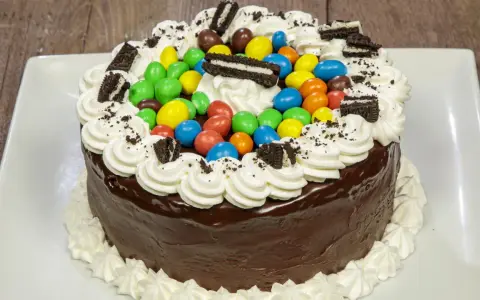 Torta al cioccolato con panna, caramelle colorate e biscotti Oreo, un'esplosione di gusto per torte di compleanno particolari.