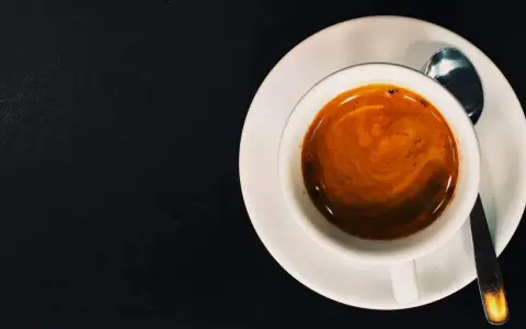 Eine Tasse Espresso mit Crema auf einer Untertasse, daneben eine kleine Löffel. Das perfekte Wasser zum Espresso.