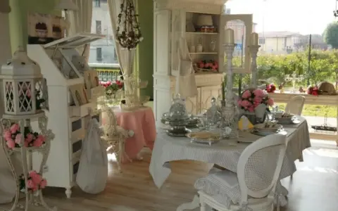 Un tavolo apparecchiato in **stile provenzale francese**, con sedie bianche, candelabri e fiori rosa.