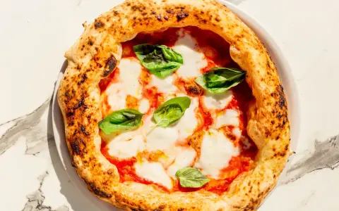 Eine köstliche Pizza Margherita mit geschmolzenem Mozzarella, Tomatensauce und frischem Basilikum. Perfekt für ein einfaches Pizza Margherita Rezept.