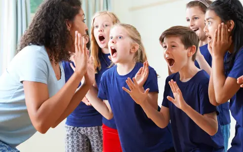 Bambini entusiasti in cerchio, con la maestra che guida attività di psicomotricità e linguaggio, stimolando espressioni vocali e corporee.