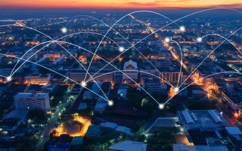 Aerial view of a city at dusk, with glowing lines connecting buildings, symbolizing modern infrastructure and networking.