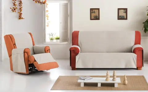 Fundas de sofá Eysa en tonos neutros y naranjas, cubriendo un sillón reclinable y un sofá de dos plazas en un salón luminoso.