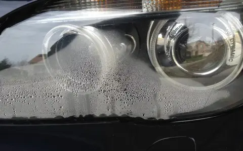 Krople wody wewnątrz reflektora BMW. Brak widocznych odpowietrzników w reflektorach sugeruje problem z uszczelnieniem.