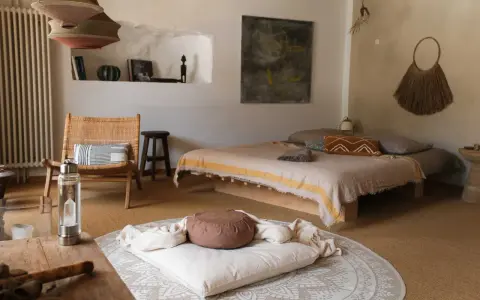 Ein gemütlicher Raum zum Meditieren einrichten: Ein Bett, ein Stuhl, Kissen und Decken laden zur Entspannung ein.