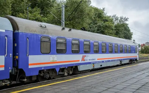 Niebiesko-szary wagon sypialny PKP Intercity stoi na torach. Wygodny przedział sypialny PKP zaprasza do podróży.