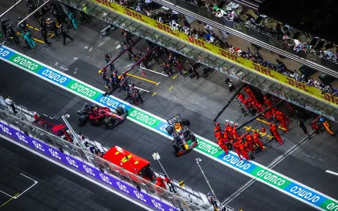 Equipos de F1 en boxes. Un coche Red Bull con un undercut f1 se detiene, mientras mecánicos de Ferrari se preparan.