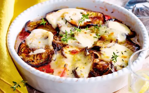 Ein köstlicher Auberginen Tomaten Auflauf mit geschmolzenem Käse und frischen Kräutern, bereit zum Genießen.