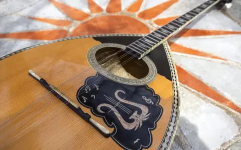 Piękny grecki instrument muzyczny, bouzouki, leży na mozaice z symbolem słońca.
