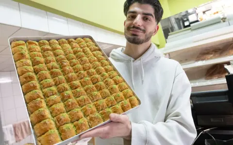Mann hält eine große Blechschale mit Baklava, bereit für das Zuckerfest.