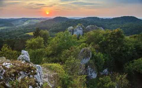 Zachód słońca nad Górami Świętokrzyskimi. Skaliste formacje i bujna zieleń tworzą malownicze krajobrazy, jedne z wielu atrakcji regionu.