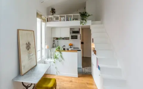 Un petit appartement optimisé avec un coin cuisine, un bureau escamotable et un escalier menant à une mezzanine. Idéal pour un **DIY rangement** créatif.
