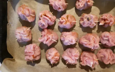 Gotowe do pieczenia sakiewki ze schabu, ułożone na papierze do pieczenia.
