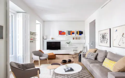 Salón moderno con sofás grises, mesas de centro y arte abstracto. Se aprecia la sutil diferencia entre blanco y blanco roto en paredes y carpintería.