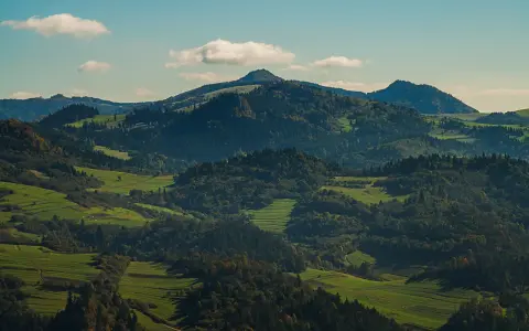 Wysokie Pieniny w jesiennej szacie, zielone pola i lasy tworzą malowniczy krajobraz.