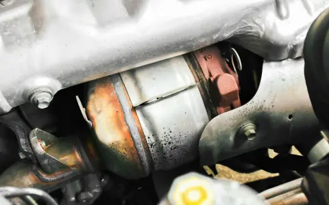 Dettaglio del sistema di scarico di un'auto, con il filtro antiparticolato (FAP) visibile. Togliere il FAP vantaggi: meno intasamenti, migliore fluidità dei gas.