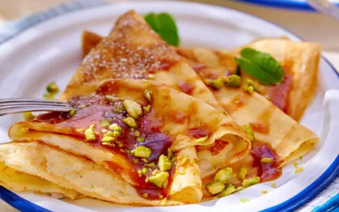 Délicieuses crêpes salées au beurre, garnies de pistaches concassées et d'un coulis rouge. Une touche de menthe apporte de la fraîcheur.