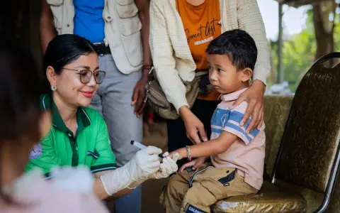 En sjukvårdare med handskar markerar ett barns finger efter vaccination i Kambodja.