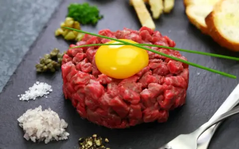 Tartare di manzo fresca e succulenta, con tuorlo d'uovo, capperi, cipolla, sale, pepe e crostini.