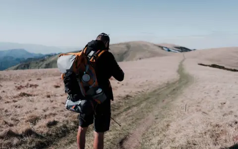 Uomo con zaino da trekking su un sentiero di montagna.