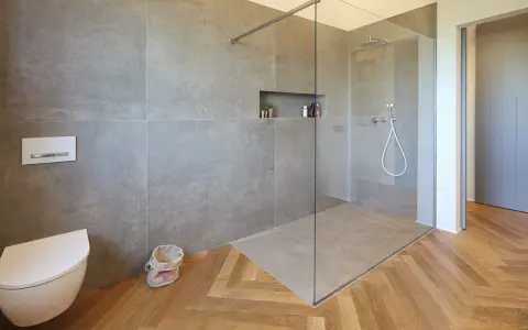 Bagno moderno con doccia walk-in, vaso sospeso e finiture in legno. Il significato di doccia walk-in è uno spazio aperto e accessibile.