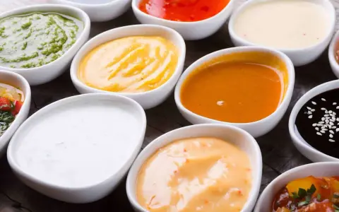 Assortiment de sauces pour raclette : verte, jaune, orange, blanche, rouge, noire. Un délice pour accompagner votre fromage fondu.