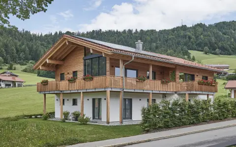 Ein modernes Holzhaus mit Balkonen und Blick auf grüne Hügel. So könnte man beschreiben, was ein Chalet in den Bergen ist.