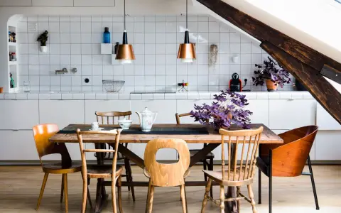 Une cuisine ouverte sur salle à manger avec un îlot central, des chaises en bois et des suspensions cuivrées.