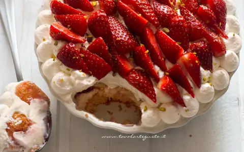 Delizioso tiramisù alle fragole, con panna montata, fragole fresche e pistacchi tritati. Una fetta è già stata servita.