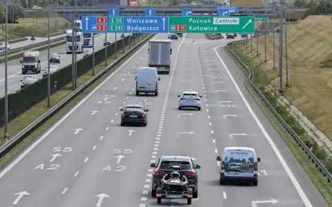 Autostrada z ruchem samochodów, znakami drogowymi kierującymi do Warszawy, Bydgoszczy, Poznania i Katowic.