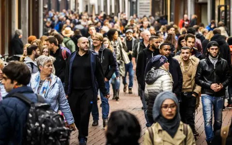 A diverse crowd of people walks down a busy street in the Netherlands.