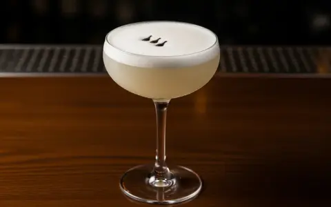En elegant Pisco Sour med skummig topp och tre små prickar. Perfekt för ett pisco sour recept.