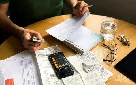 Rozliczenie PIT i upadłość konsumencka: rachunki, kalkulator i dokumenty na stole sugerują trudną sytuację finansową i potrzebę uporządkowania spraw.