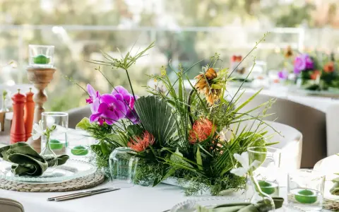 Stylowe podziękowania dla gości w duchu "less waste": bukiet z orchidei, protei i paproci, zielone serwetki, świece w szkle.