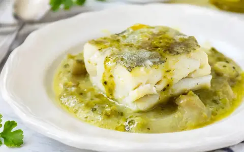 Un trozo de merluza a la vasca, jugoso y tierno, bañado en una salsa verde cremosa con trozos de pimiento.