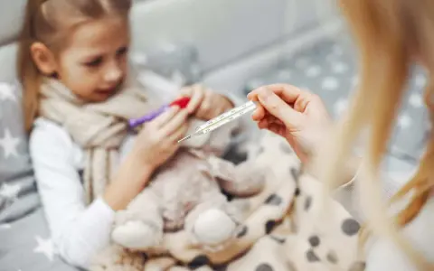 Chora dziewczynka z gorączką, mama mierzy temperaturę. Czy to rotawirus?