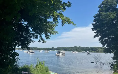 Boote auf dem Glindower See unter blauem Himmel, umgeben von grünen Bäumen. Ein sonniger Tag am Wasser.