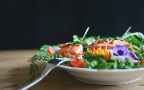 En vacker sallad med lax, tomater och ätbara blommor. Perfekt för att deffa mat och njuta av en hälsosam måltid.