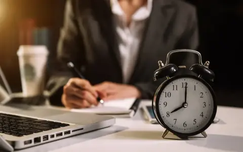 Zegar pokazuje 8:00. Osoba pisze notatki, pracując w grudzień dni pracujące.