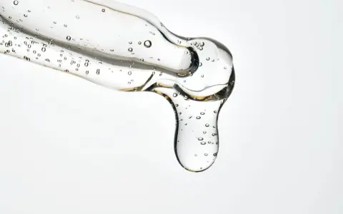 Kwas salicylowy działanie: przejrzysty żel z pęcherzykami powietrza spływa z pipety, obiecując czystą i odświeżoną skórę.