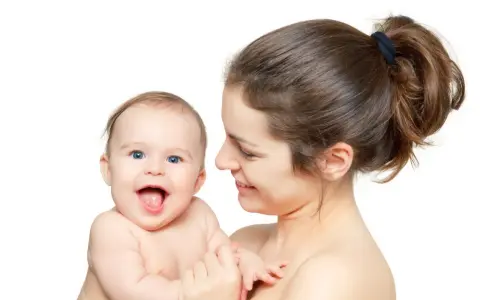 Uśmiechnięta mama tuli radosne dziecko. Pomimo nerwowa atmosfera w domu, dziecko rozjaśnia wszystko swoim uśmiechem.