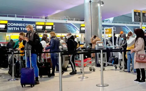 Kolejka do odprawy na lotnisku, przypominająca terenową delegaturę paszportową w Bielsku-Białej. Ludzie z bagażami czekają na swoją kolej.