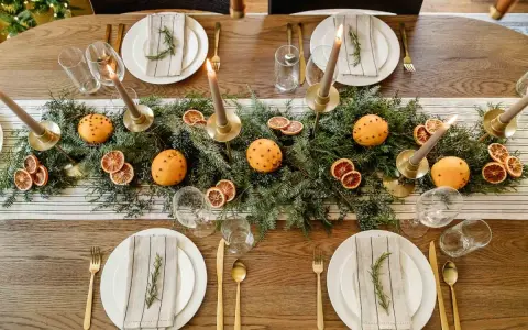 Vackert dukat julbord med granris, apelsiner med nejlikor, torkade apelsinskivor och ljus. En perfekt inspiration för att dekorera julbordet.